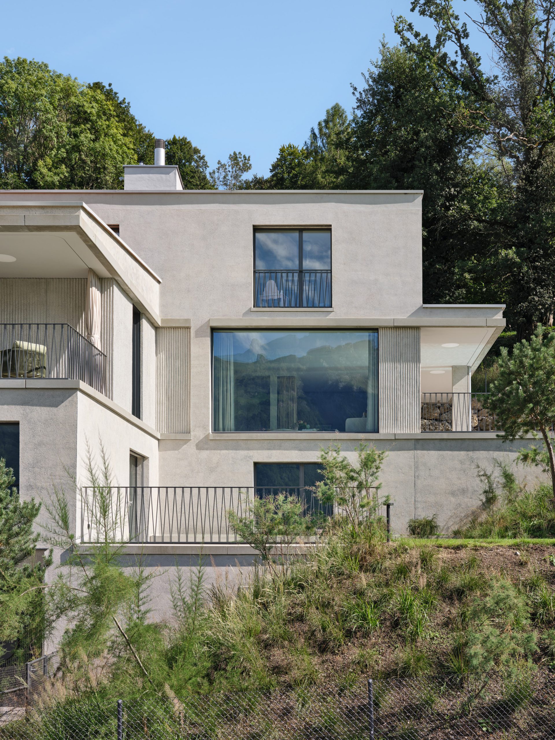 Haus W, a modern residence designed by Studio EH, integrated into a dramatic hillside with visible rock formations.