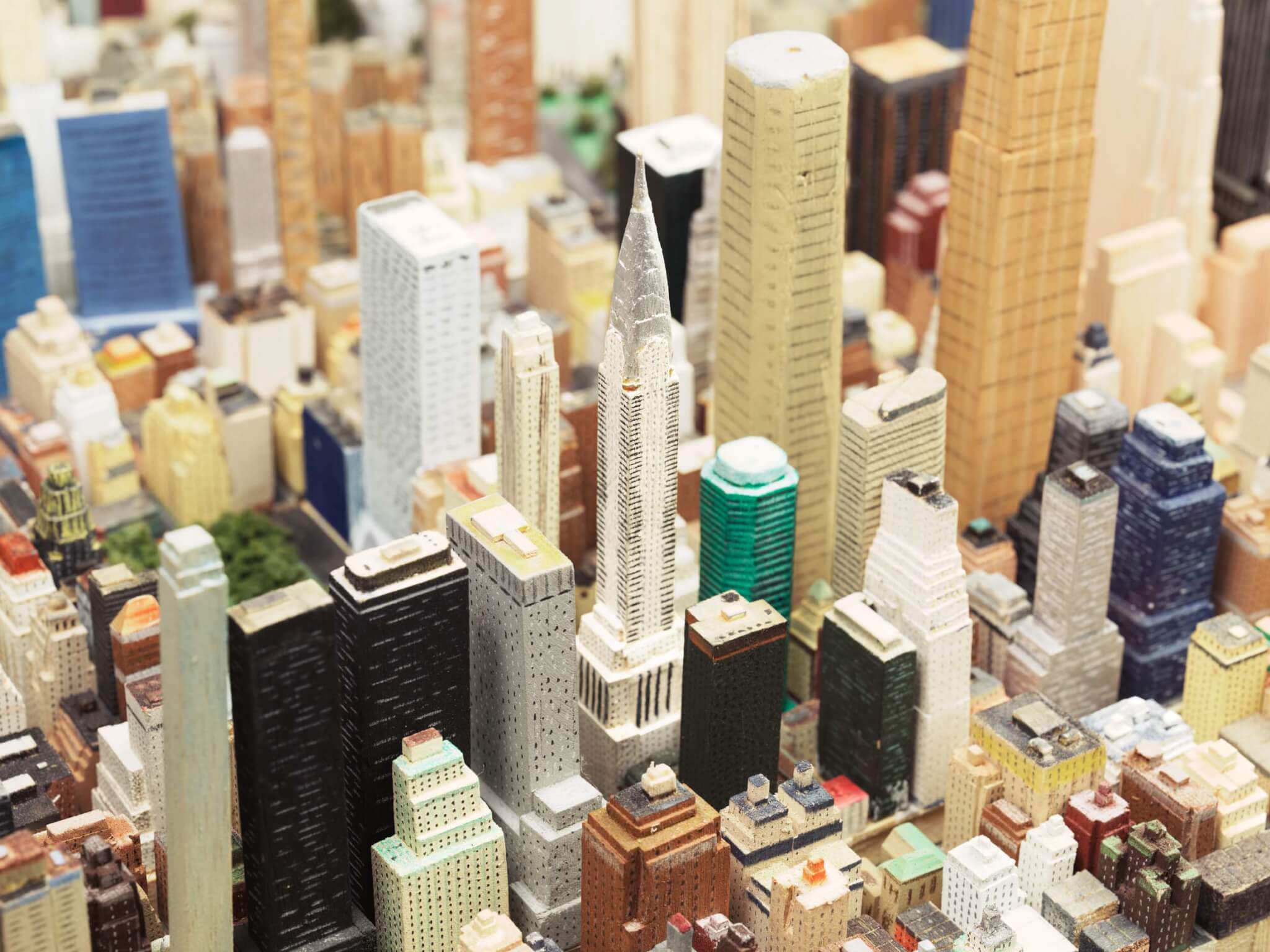A detailed, hand-carved miniature model of New York City, showcasing numerous buildings and streetscapes.
