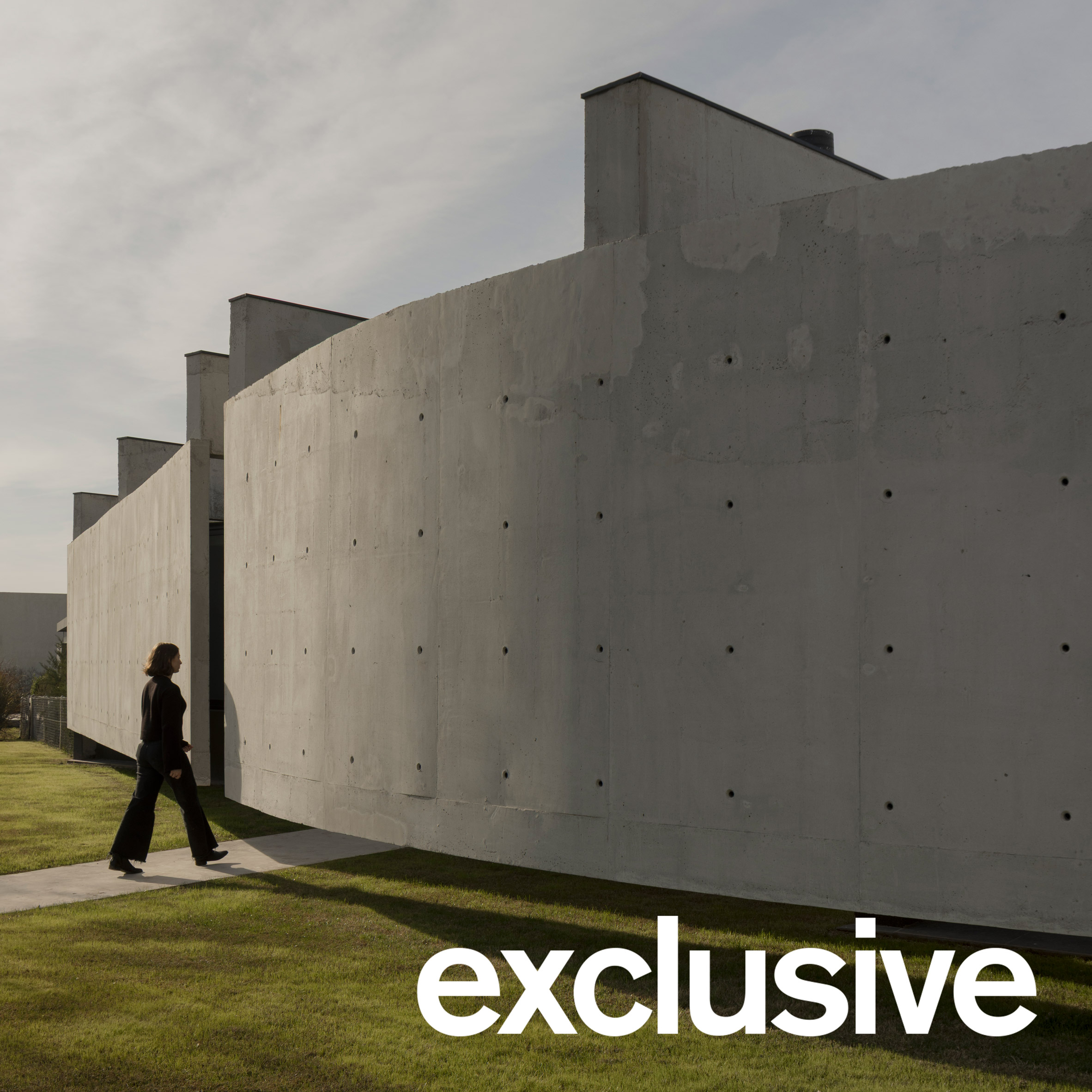 Exterior view of Casa Alba II by Además Arquitectura, showcasing its rounded concrete privacy wall and monolithic presence within a suburban Buenos Aires setting.