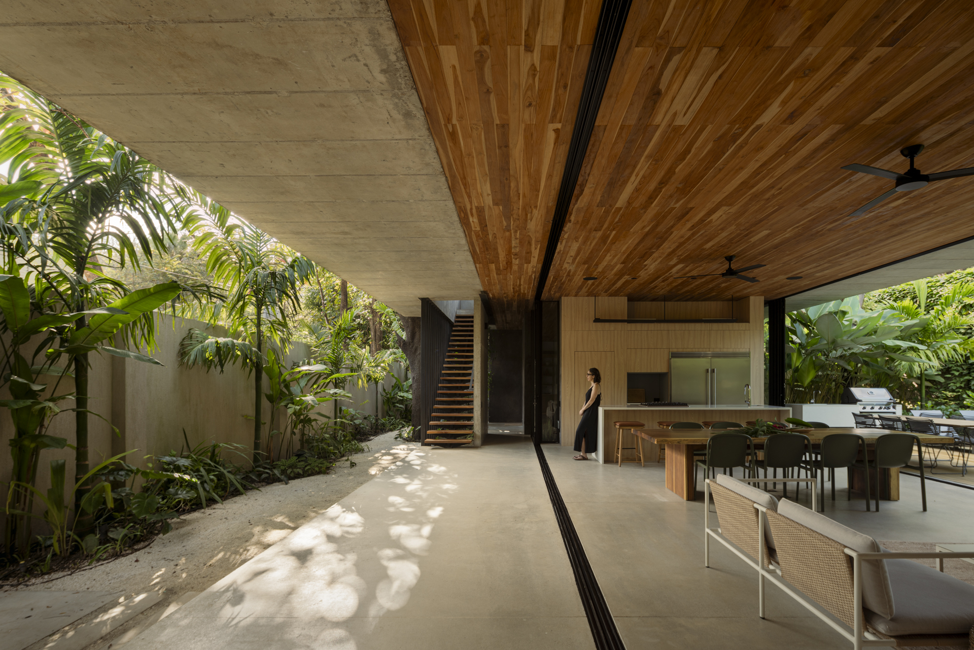 Exterior view of The Calm House, showing its integration with the surrounding forest and a unifying roof structure.