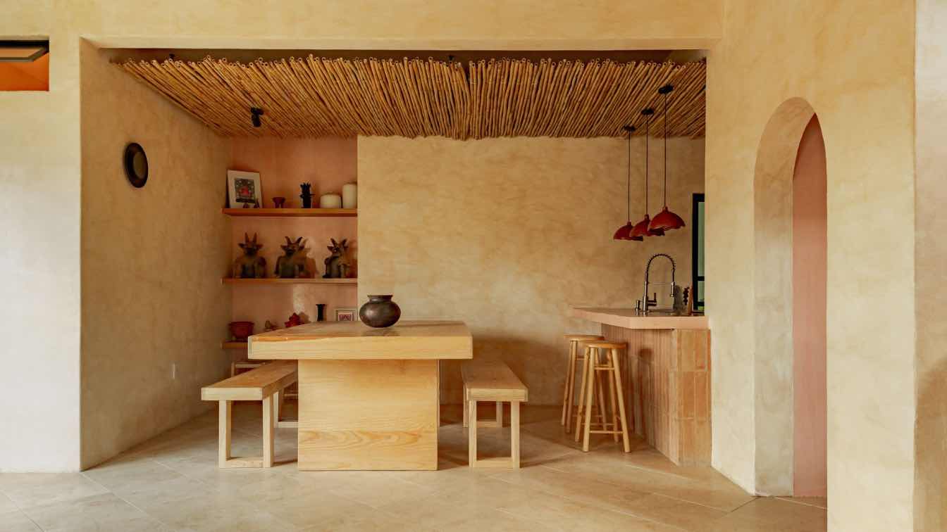 Interior view of Casa Luz in Oaxaca, showing limewash walls, a curved archway, and natural light illuminating textured surfaces and Oaxacan artisan details.