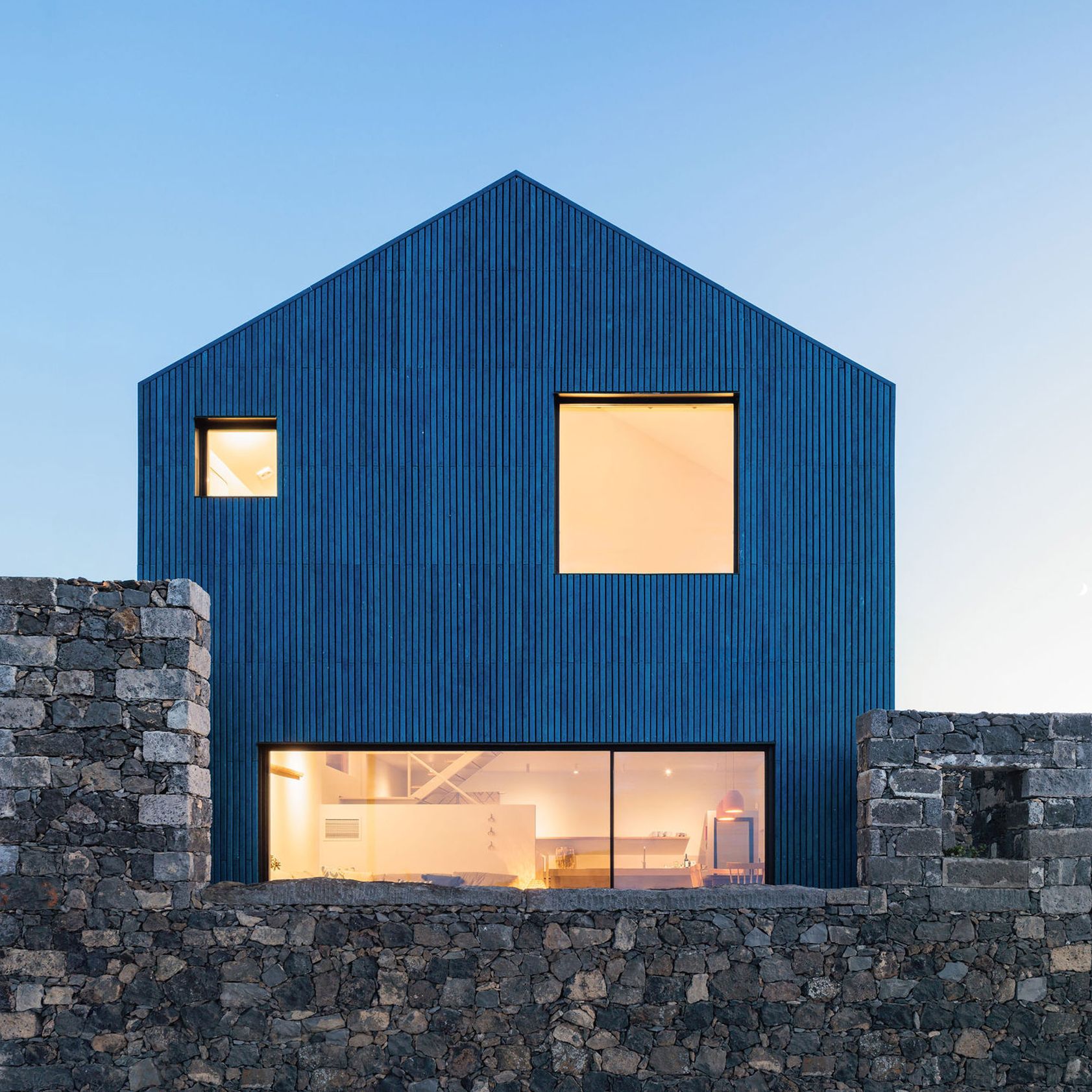 Exterior view of The Blue House, a blue-clad structure on a clifftop overlooking the ocean in the Azores.