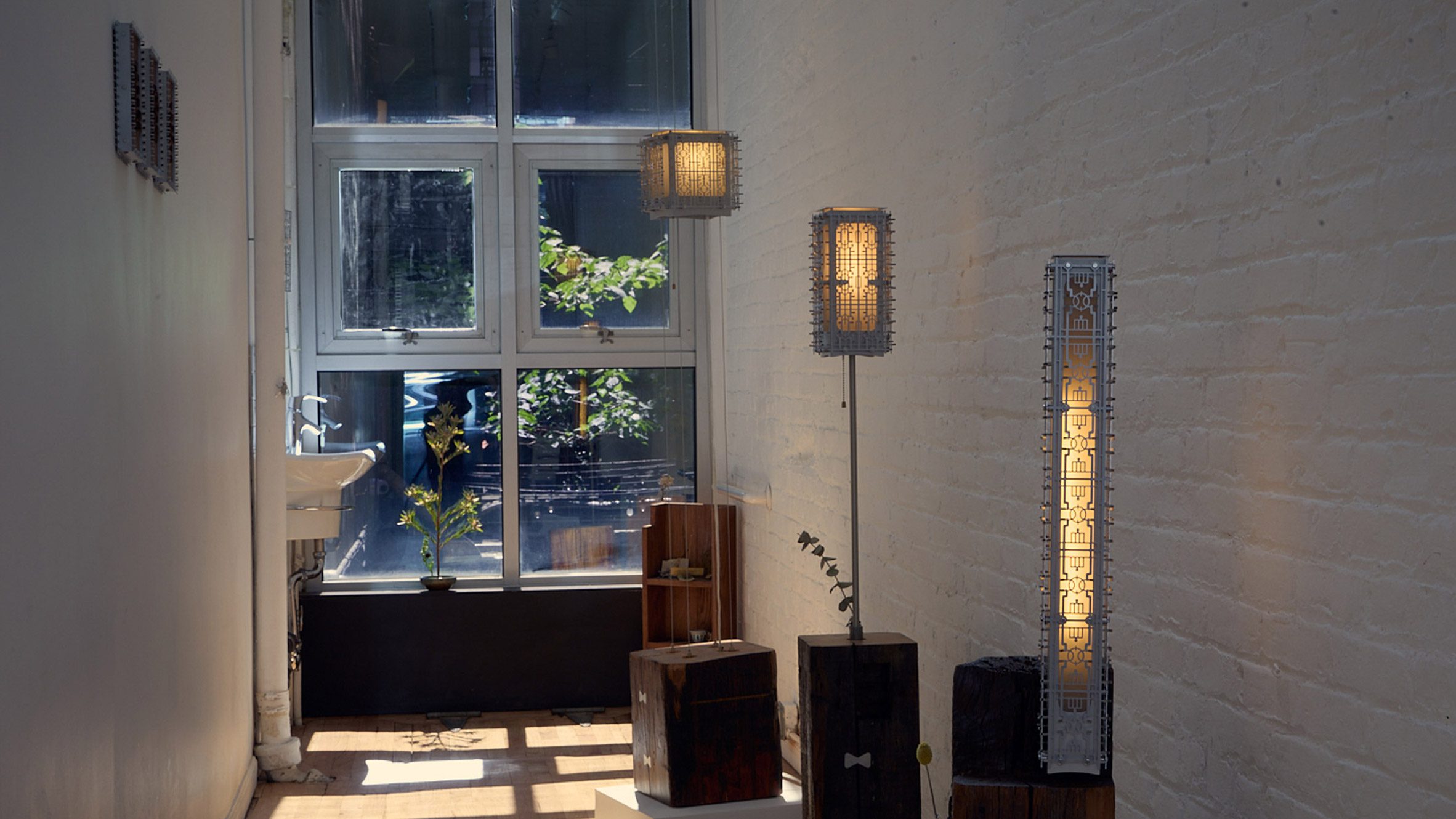 Laser-cut metal lamp by Bechara Maalouf with intricate lattice pattern, displayed on a recycled-wood base, inspired by Lebanese window guards.