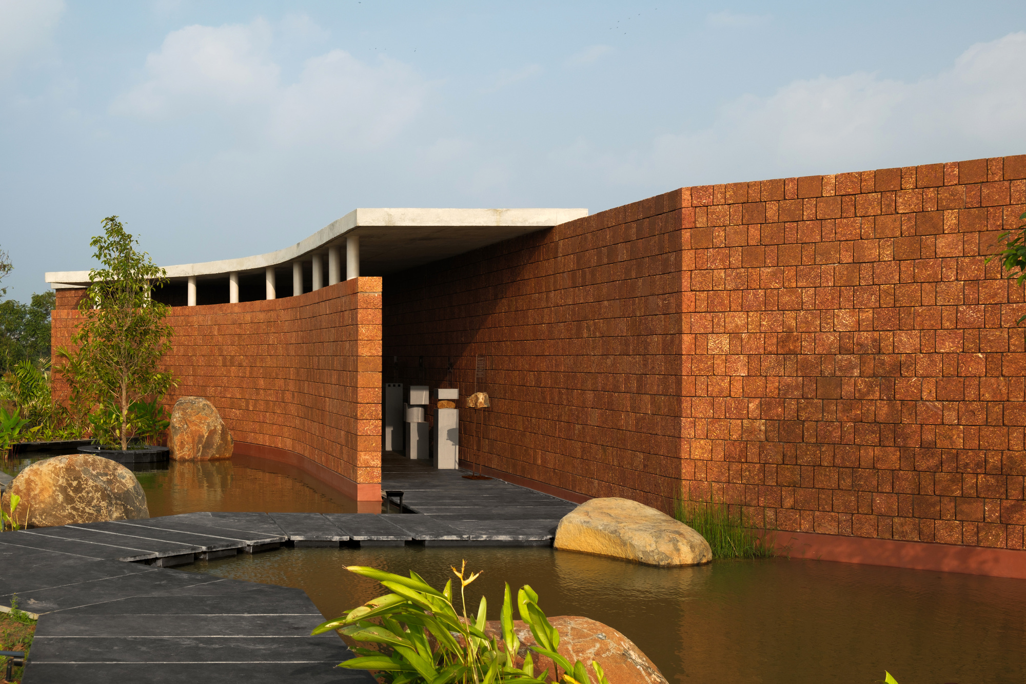 The Four Walls Pavilion, a contemporary concrete and brick structure, situated on the edge of a lake.
