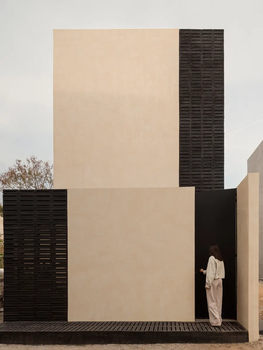 Exterior view of the WIDOARQUITECTOS office building, showcasing its strong and sober facade on a narrow lot.