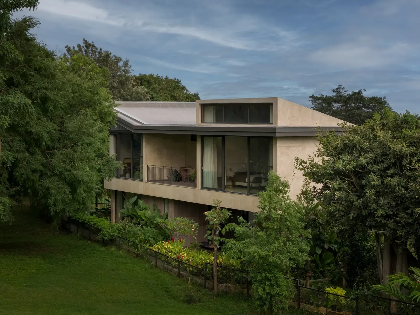 Exterior view of the Sandstone House, showcasing its sandstone facade and lush green surroundings, with a glimpse of the central courtyard.