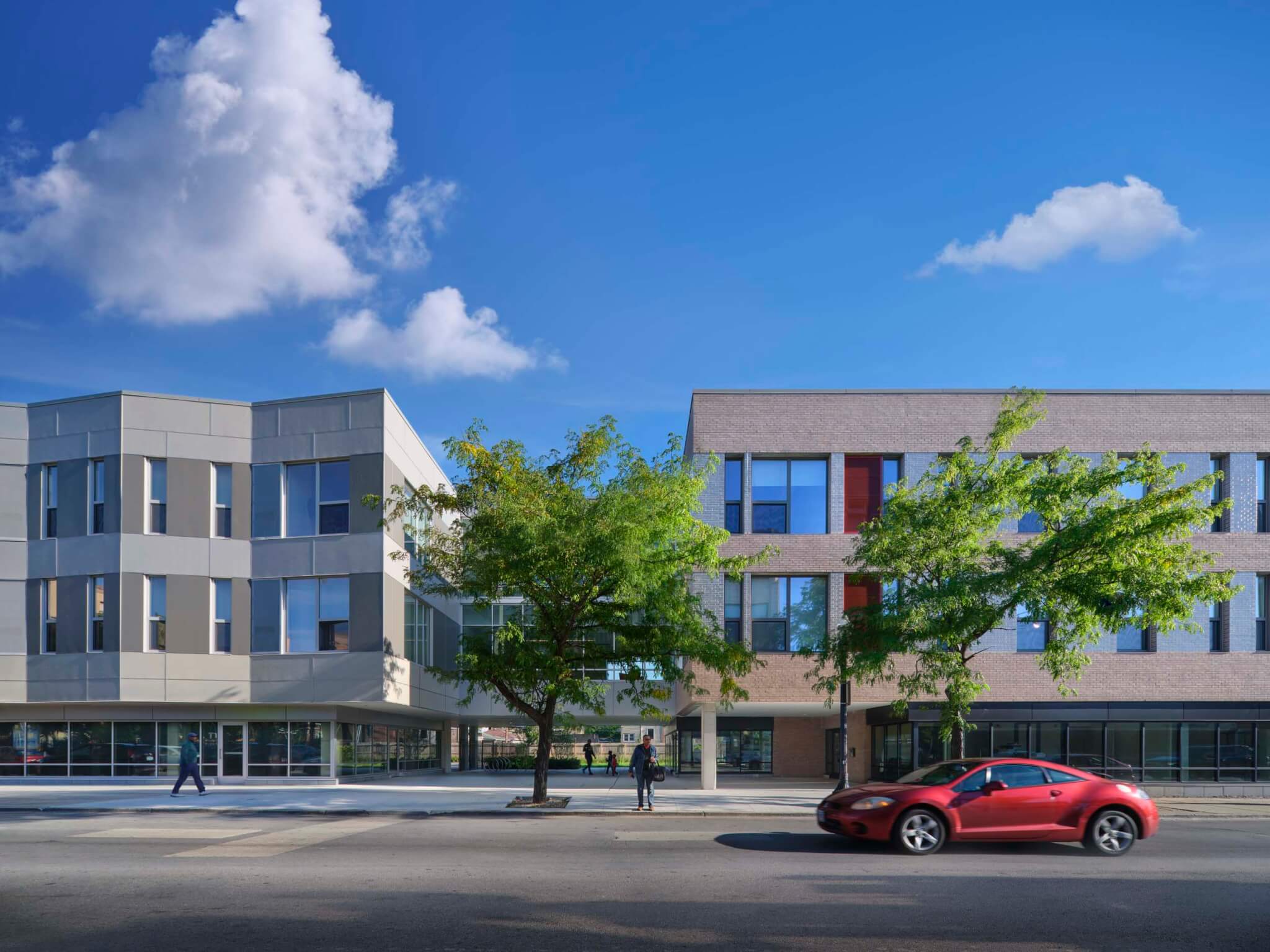 Modern mixed-use buildings with varied facade treatments and balconies line a commercial street in Chicago's Auburn Gresham neighborhood.