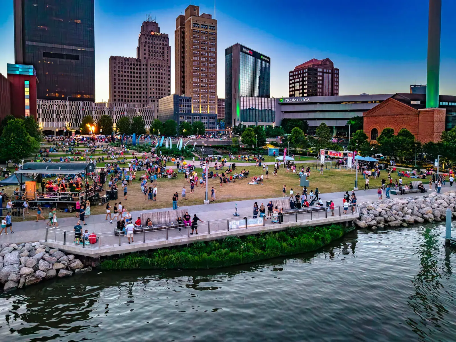 Aerial view of the Glass City Riverwalk in Toledo, Ohio, showcasing its expansive green spaces, waterfront promenade, and connection to the urban core.