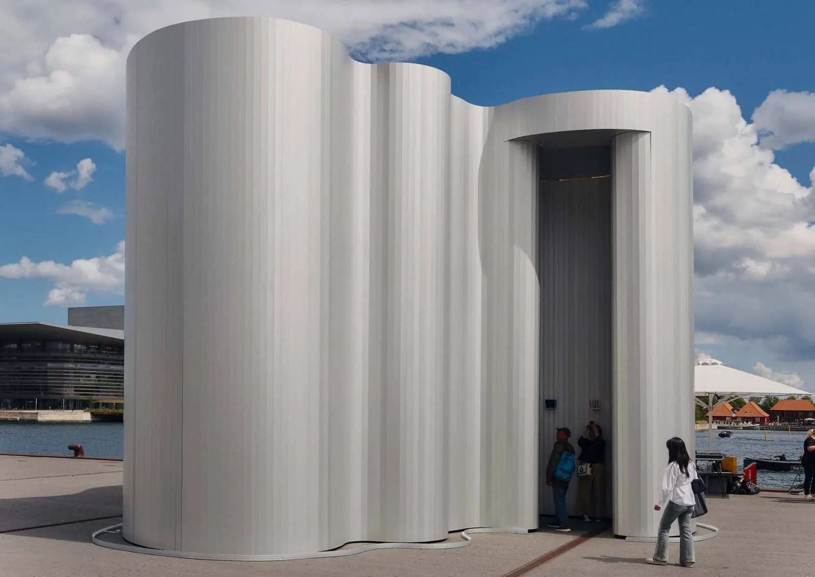 Interior view of the Aalto 90 Pavilion, showcasing the organic, curved aluminum walls and a collection of Aalto vases.