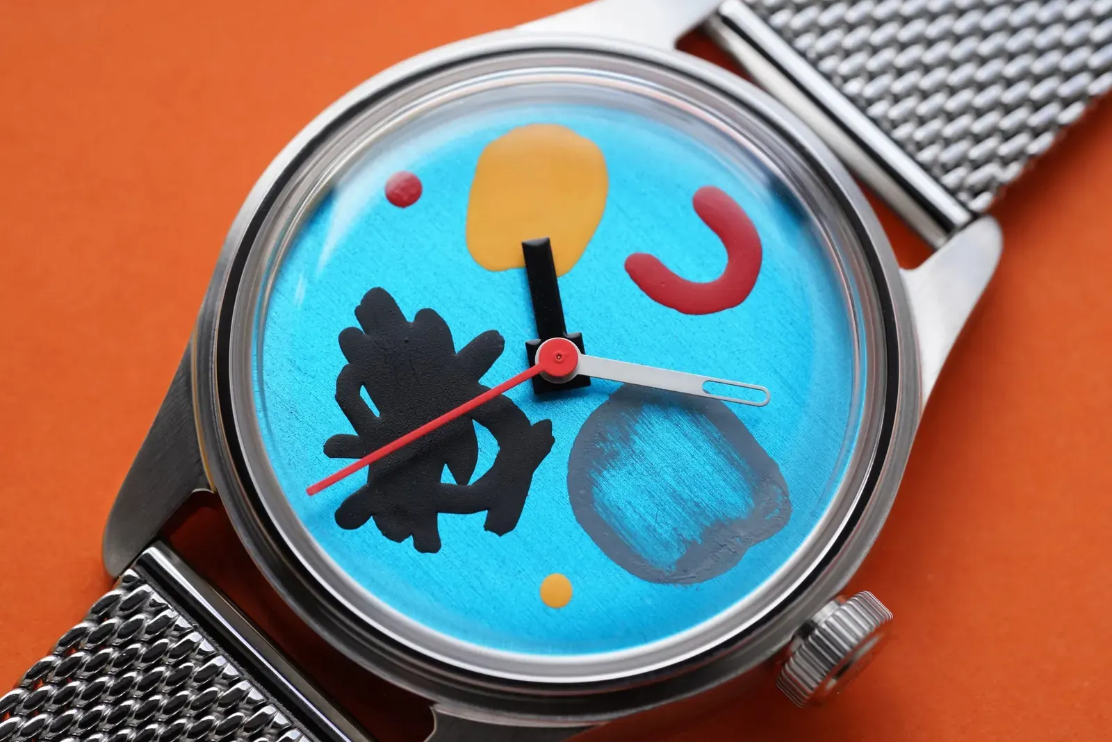 A close-up of a luxury watch dial featuring a detailed hand-painted abstract design by an artist.