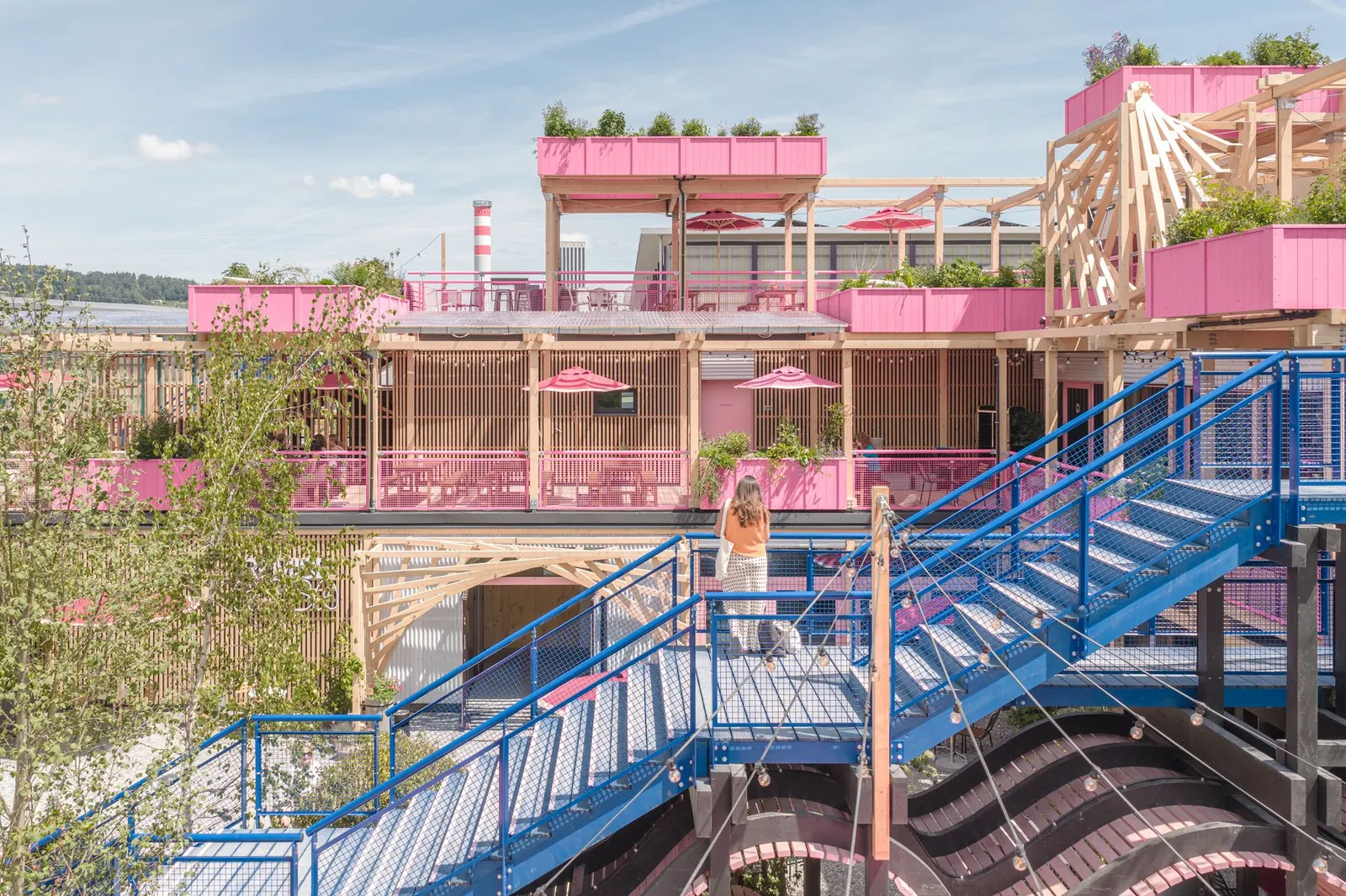 The exterior of Remise Rosa, a multi-level complex clad in rosy pink timber, situated on a former railway site in Zurich.