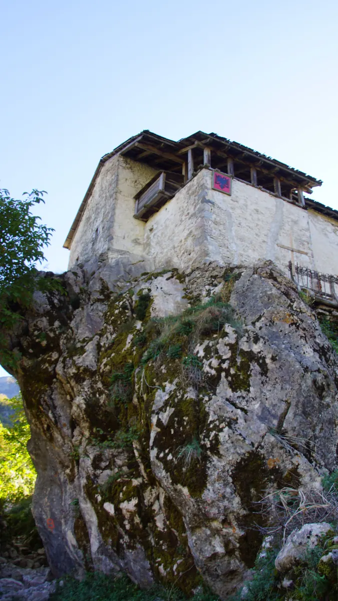 Exterior view of the Museum Tower House in Los Angeles, showcasing its slender vertical form and textured plaster facade against a hillside backdrop.