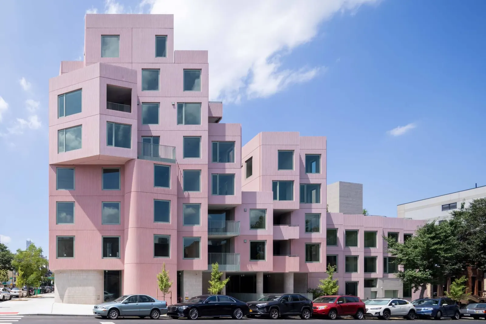 A contemporary residential building in Brooklyn with a porous facade featuring balconies, courtyards, and angled floorplans.