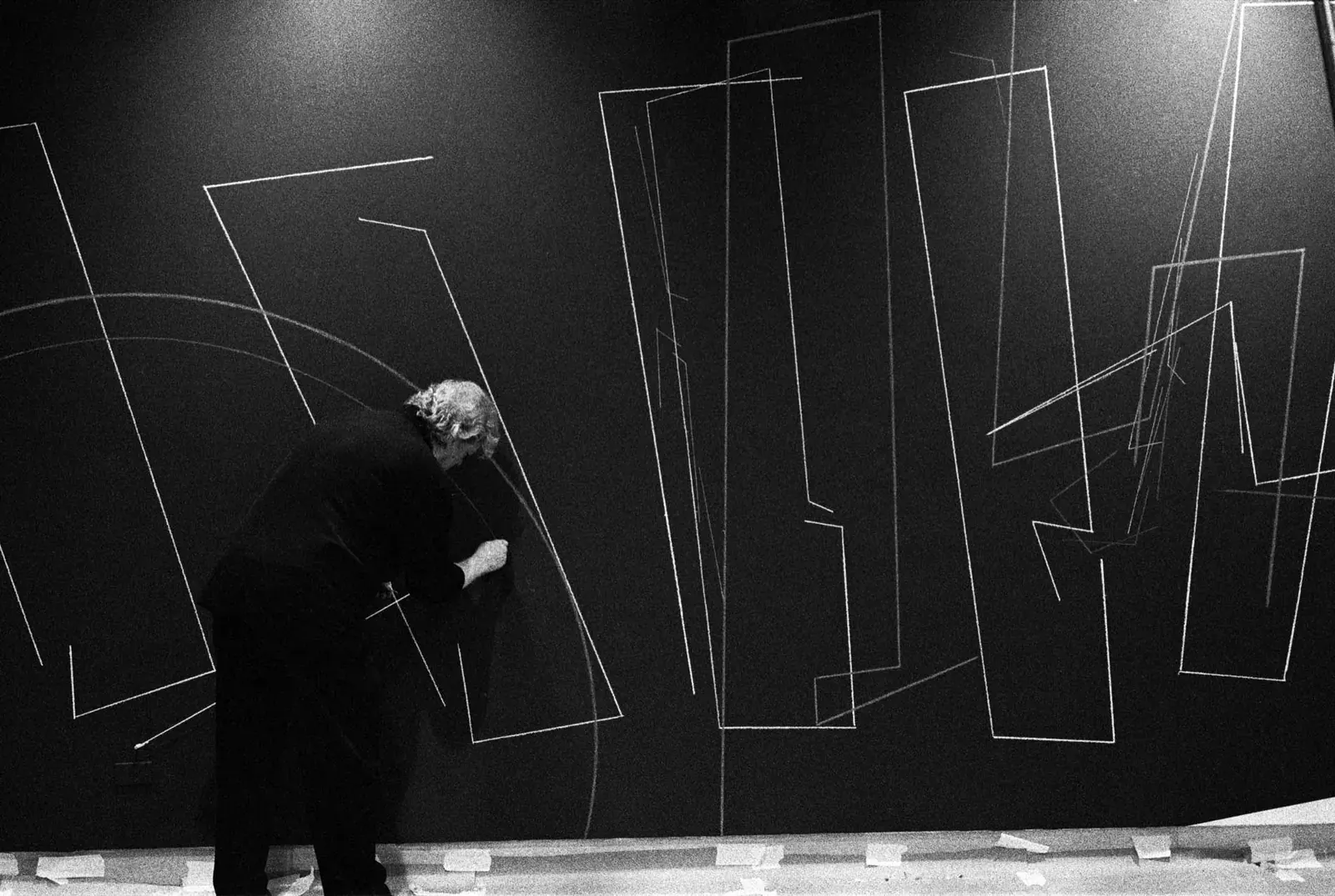 A striking architectural drawing by Lebbeus Woods, featuring complex lines and forms, displayed in an exhibition setting.