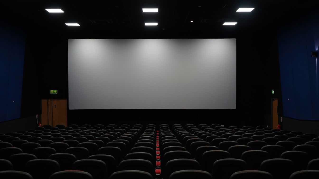 A luxurious modern home cinema featuring a large, acoustically transparent screen, plush seating, and subtle integrated lighting.