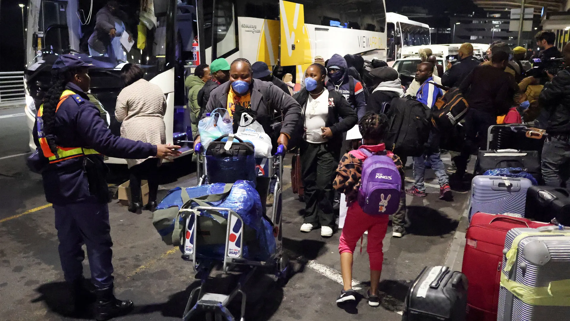 Nigerian migrants with their belongings at a departure point in South Africa, indicating their flight from xenophobic tensions.
