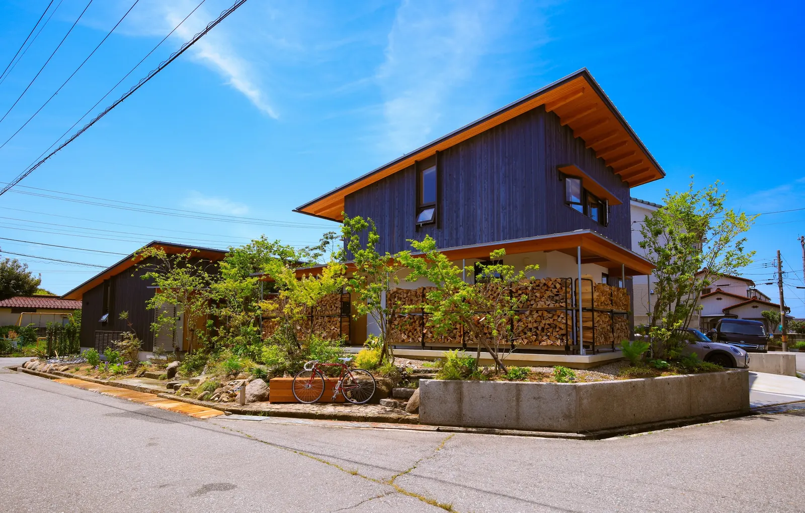 Exterior view of the Machikado Project in Toyama, Japan, designed by Plan 21, highlighting the separation and connection of the two residential buildings via a courtyard.