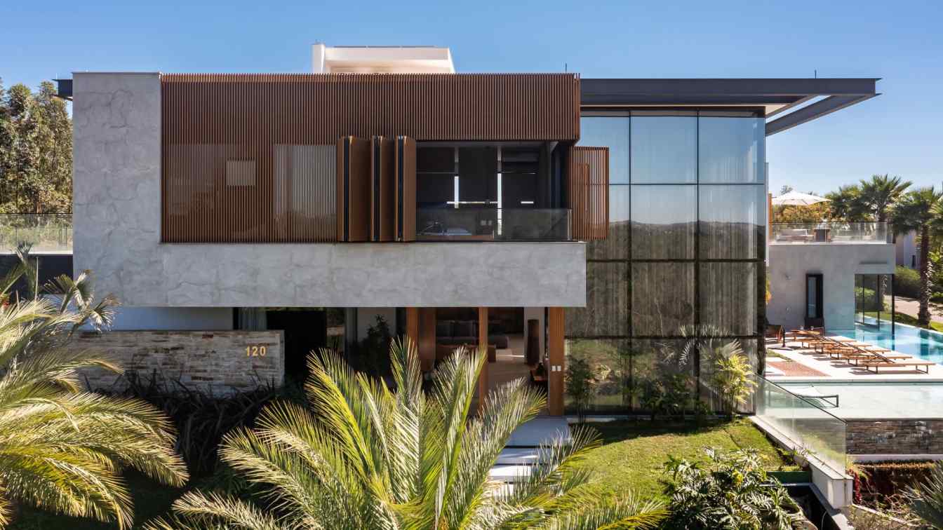 Exterior view of a modern 'U'-shaped house in Brazil, featuring an infinity pool and panoramic valley views.