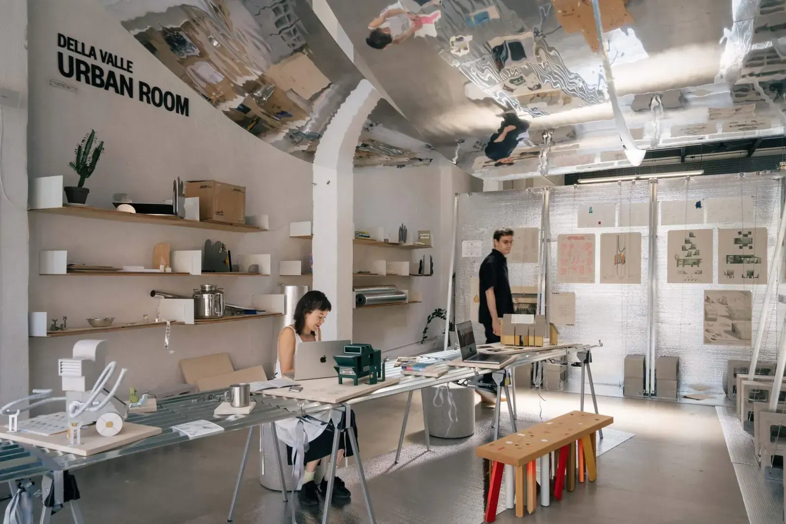 A view of the NOT NOT exhibition space at the Van Alen Institute, showing modular displays and a workspace setup.