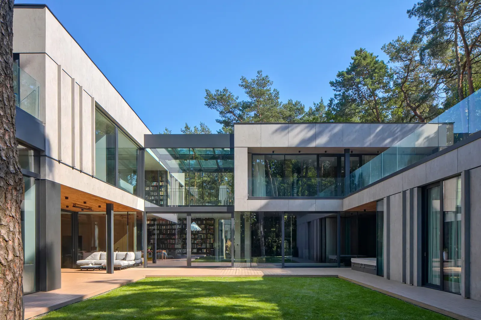 The BBB House features large windows and natural materials, blending into the lush landscape of Konstancin.