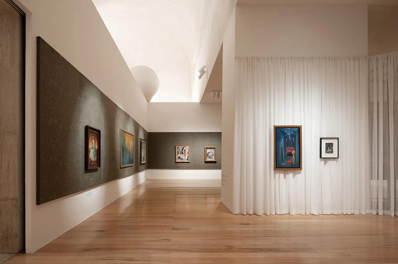 Interior view of the "Constelaciones y derivas" exhibition, showcasing artwork and architectural design elements.