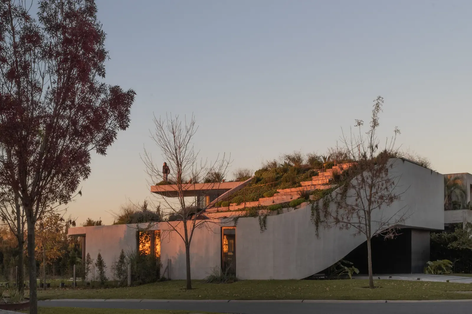 Exterior view of GP House by AtelierM, highlighting its concrete construction and unique spiral form against a backdrop of water and neighborhood context.