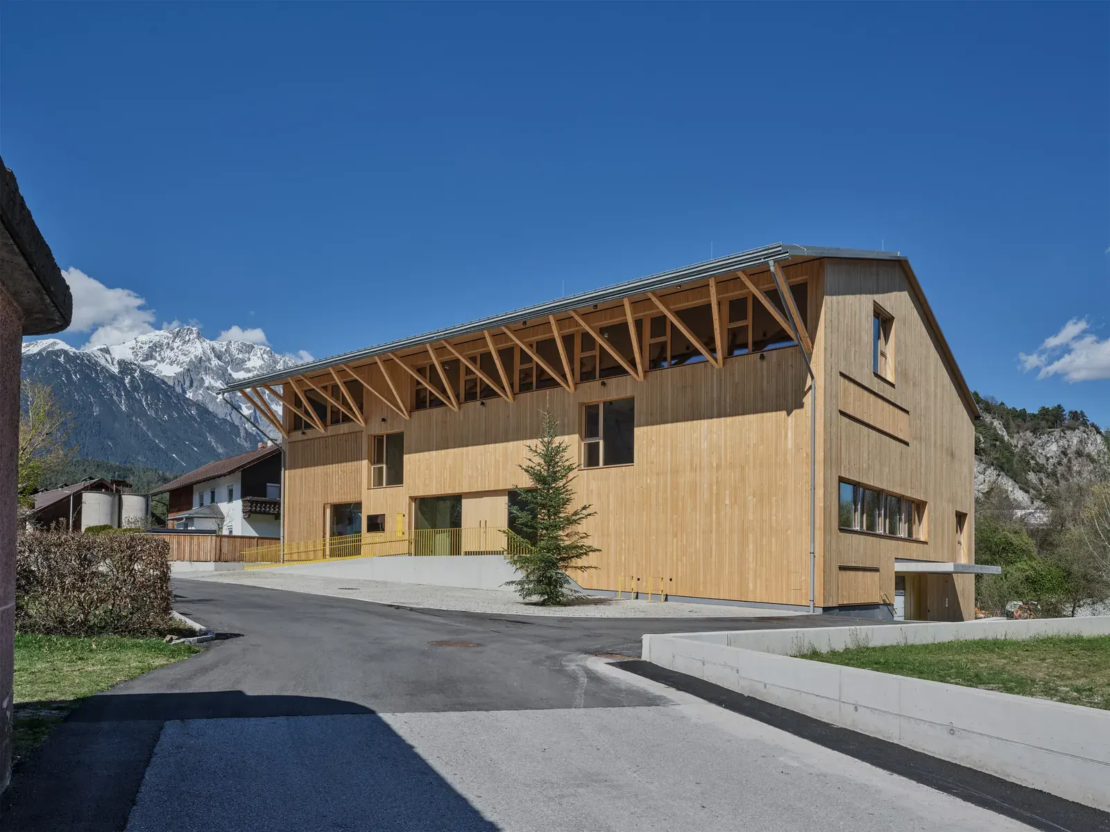 Exterior view of the Mötz Fire and Community Hall, showcasing its modern design and integration with the surrounding village landscape.
