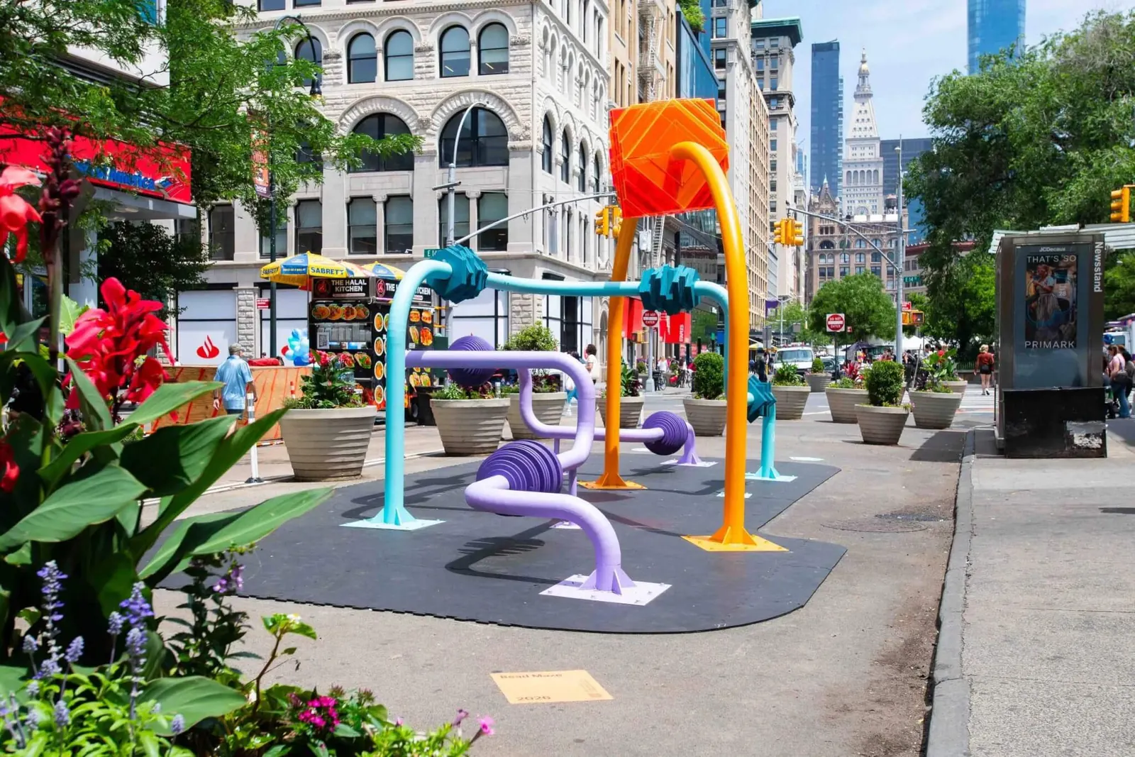 A large, colorful interactive "Bead Maze" art installation is set up in Union Square, inviting visitors to engage with its towering pipes and movable beads.