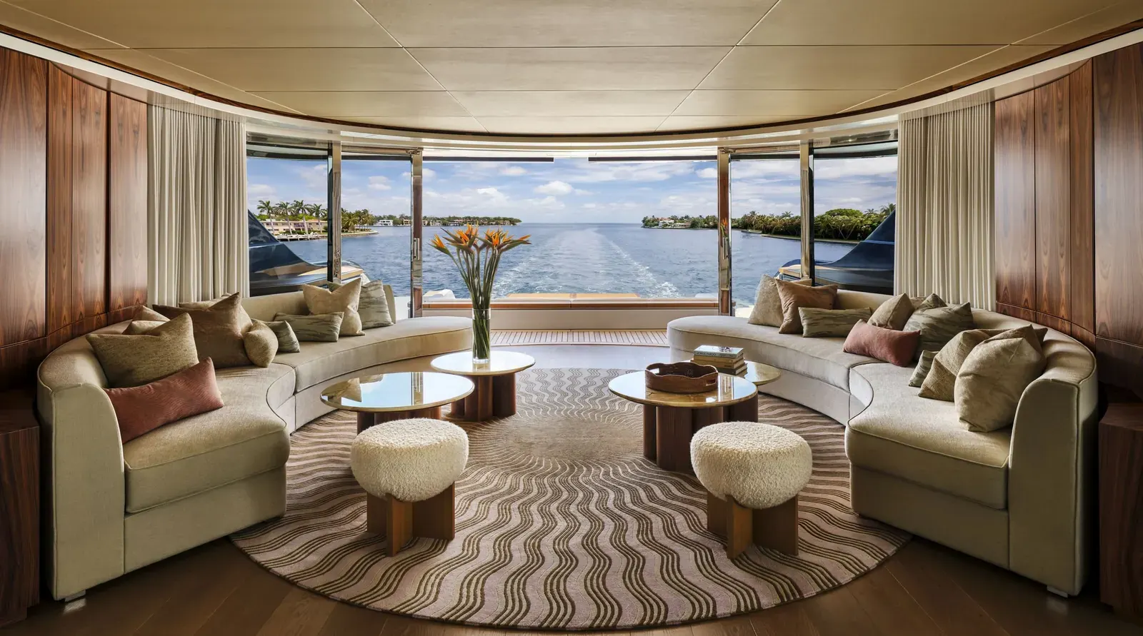 Interior of a luxury yacht featuring warm wood paneling, comfortable seating, and large windows, designed with a residential feel.
