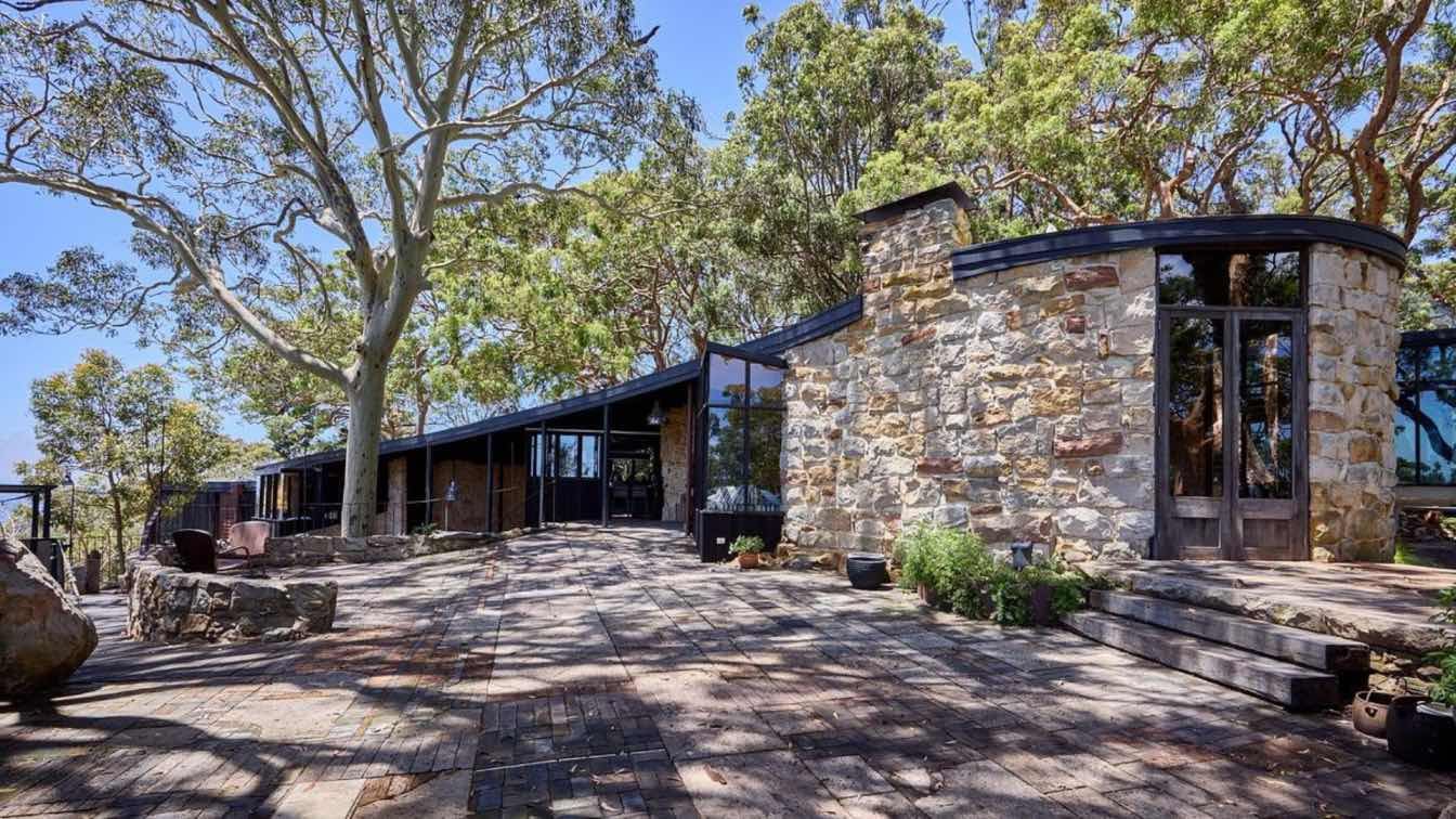 Exterior view of Babylon House showcasing curved stonework and modernist architectural details overlooking Pittwater.