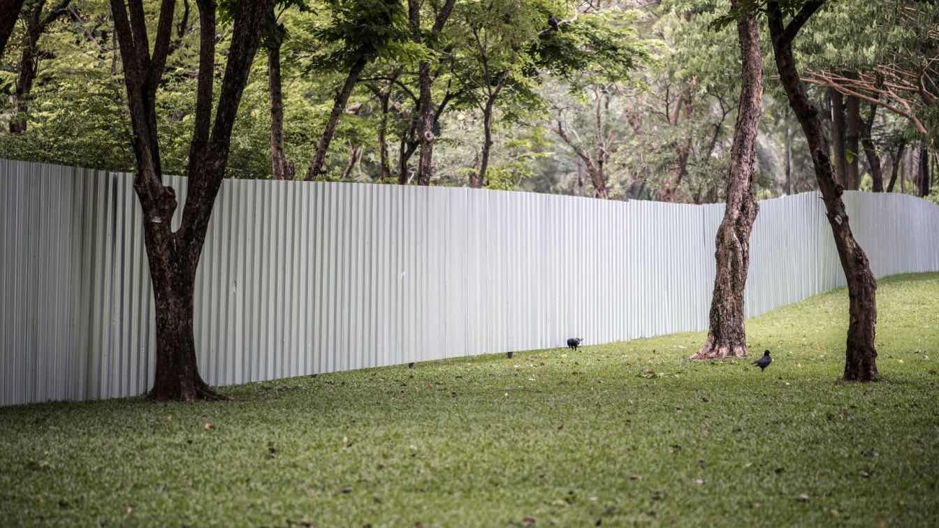 Modern architectural fencing with horizontal slats and integrated greenery, framing a residential property.