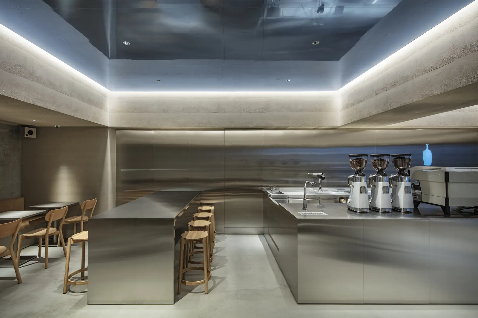 Interior of Blue Bottle Coffee Harajuku cafe, designed by TEKI Design, featuring concrete walls, steel elements, and a narrow sky opening between buildings