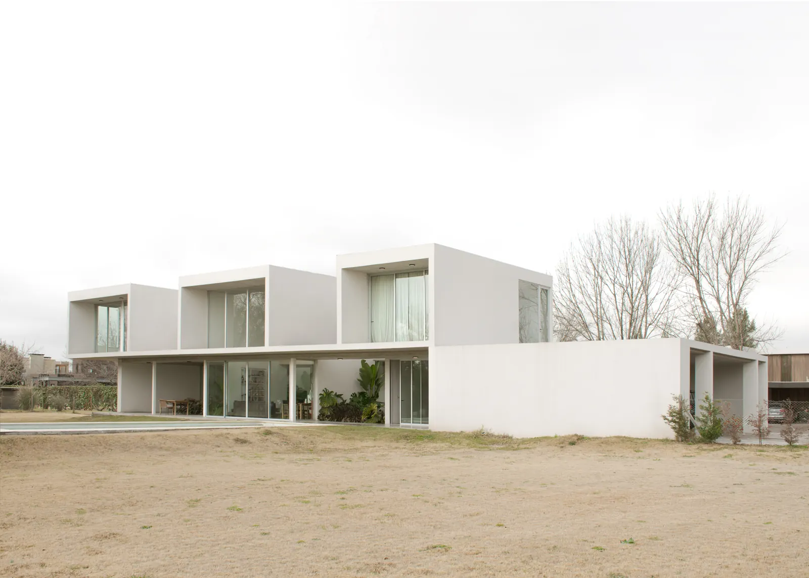 O House by YES! Architects in Pilar, Argentina, featuring a long, windowless south façade and a corner entrance.