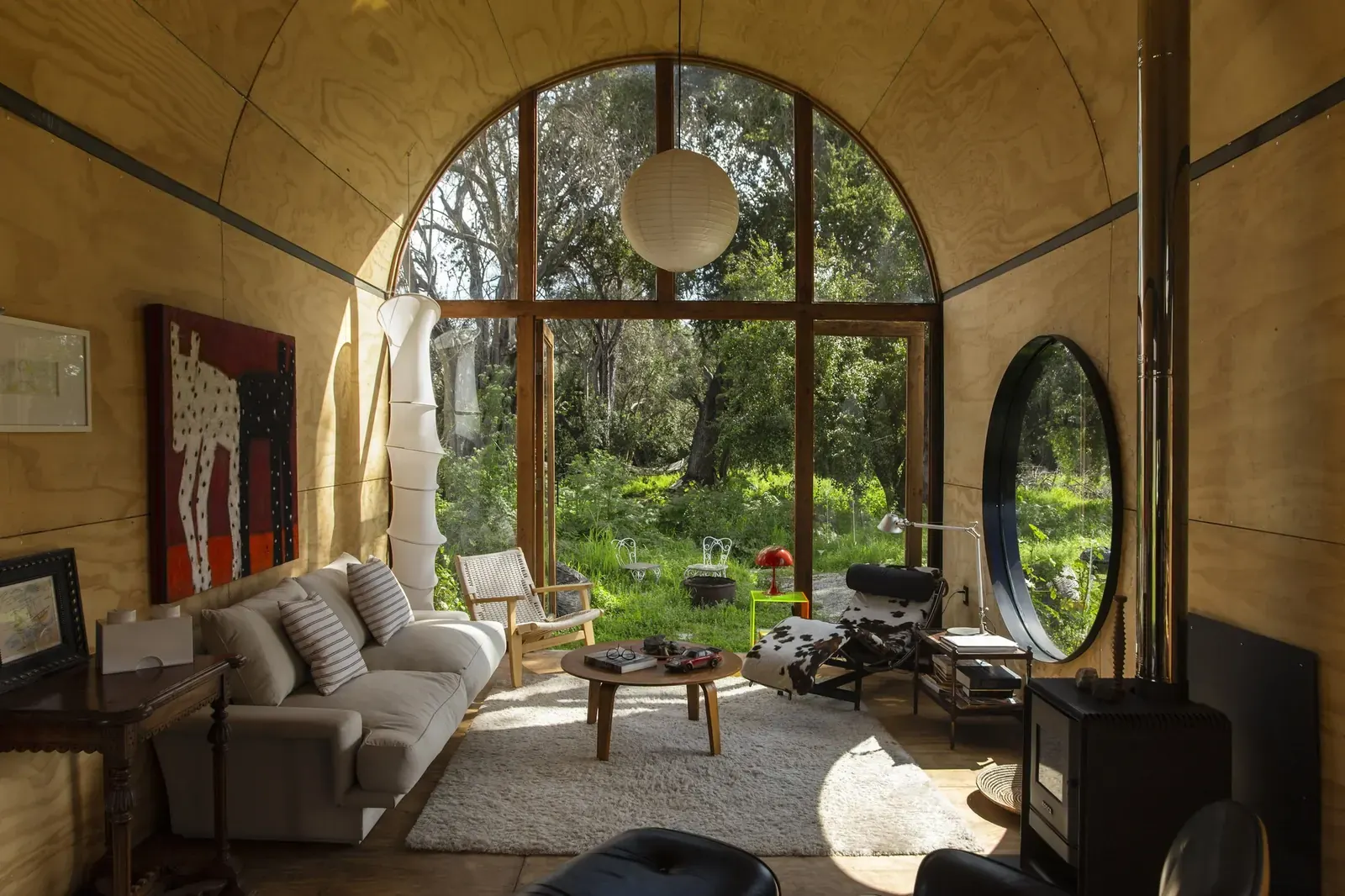 Exterior view of Catalejo house by Tololo Ugarte, a wood-and-steel structure set among four ancient trees in a seasonal pasture in Limache, Chile.