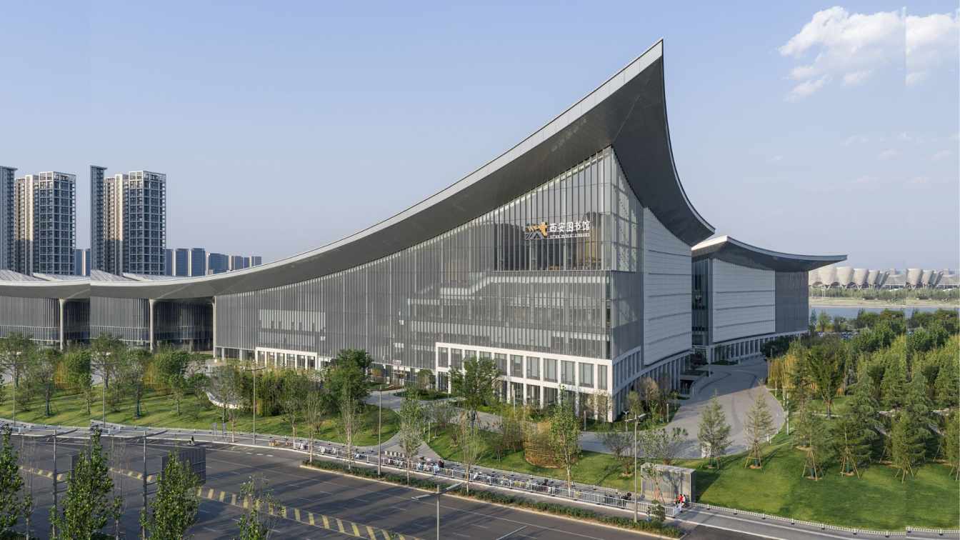 Interior view of Chang'an Academy Xi'an Public Library atrium with curved seating, multiple levels of reading platforms, and natural light, emphasizing human-scale design.