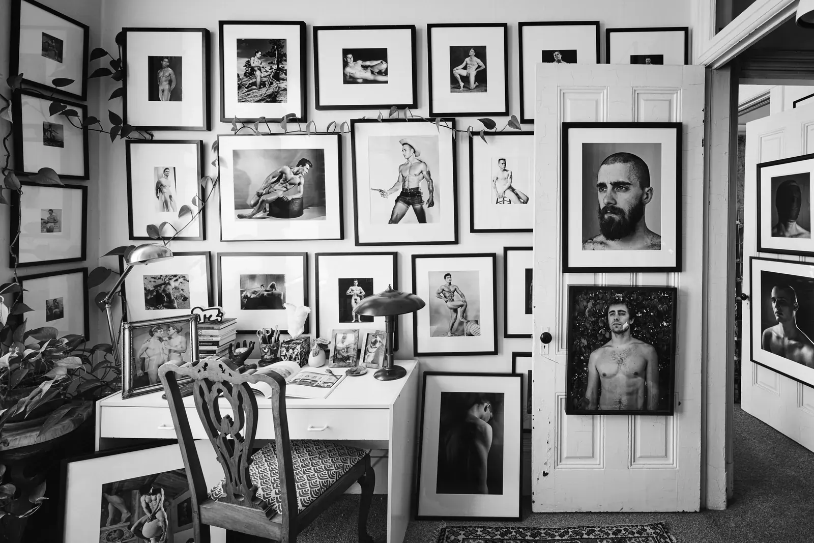 The guest bedroom in Ron Zuckerman’s San Francisco flat lined with works by photographer Danny Fitzgerald, a quilt on the bed, and a cabinet with a piece by Slava Mogutin