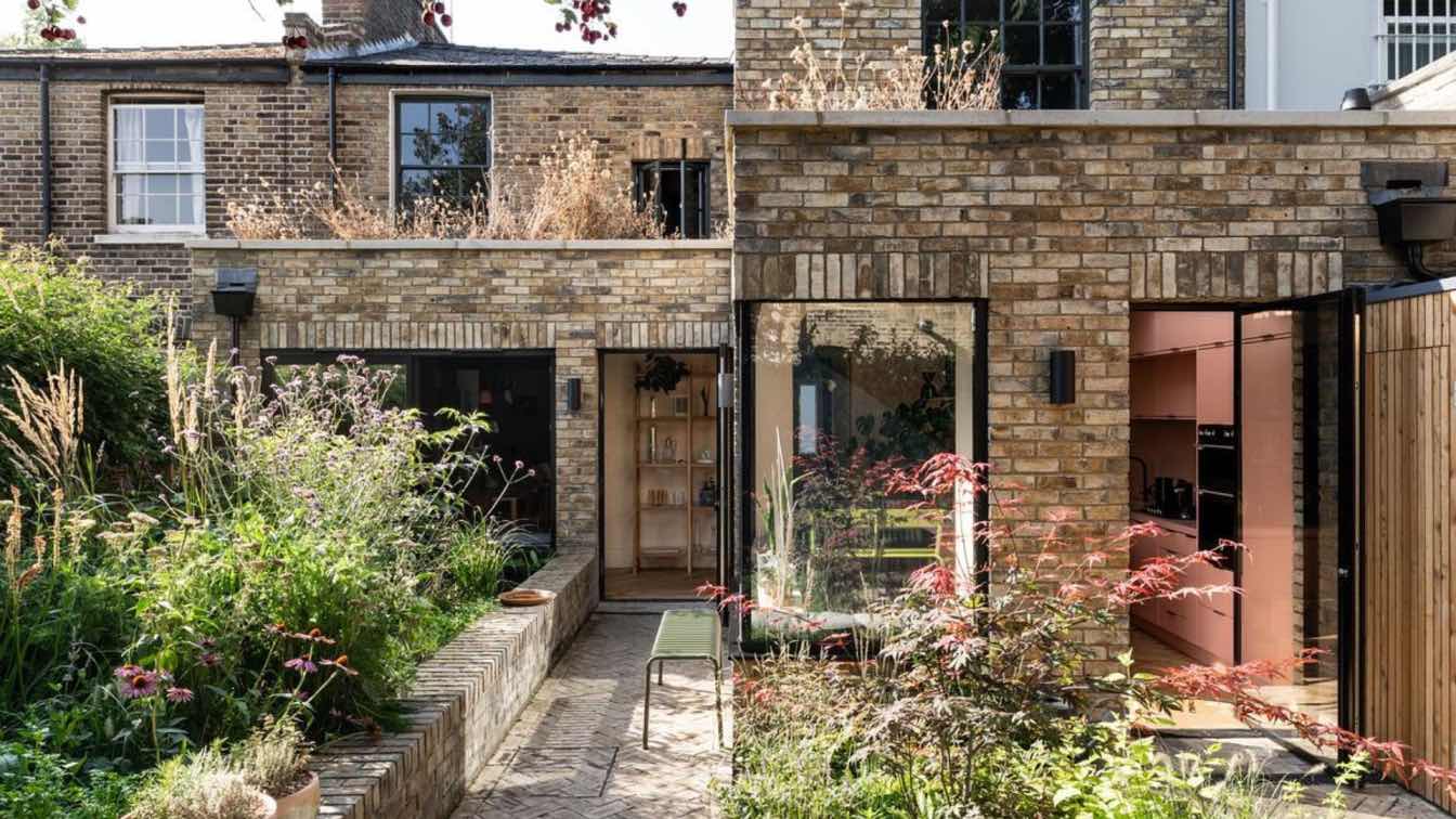 Rear view of Hawthorn House in London featuring a stepped brick extension and a wild prairie-style garden.