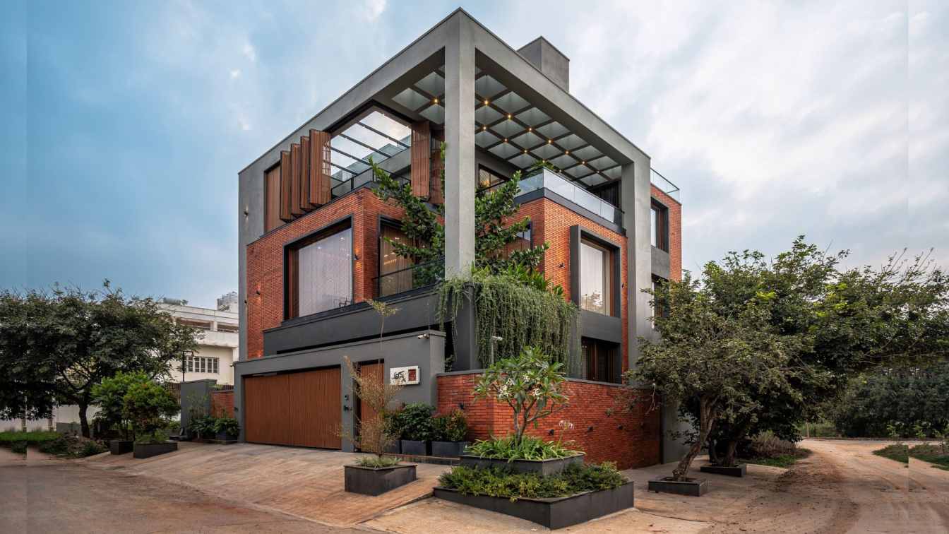 Exterior view of the House of the Framed Atrium in Bengaluru, showcasing its layered volumes and integration with a mature tree.