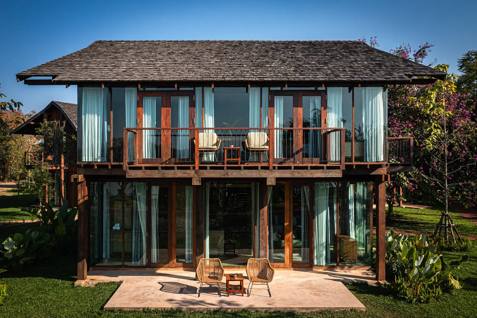 Exterior view of Nachan The Antique Courtyard Hotel, featuring a cluster of buildings with wooden accents nestled amid trees and courtyards.
