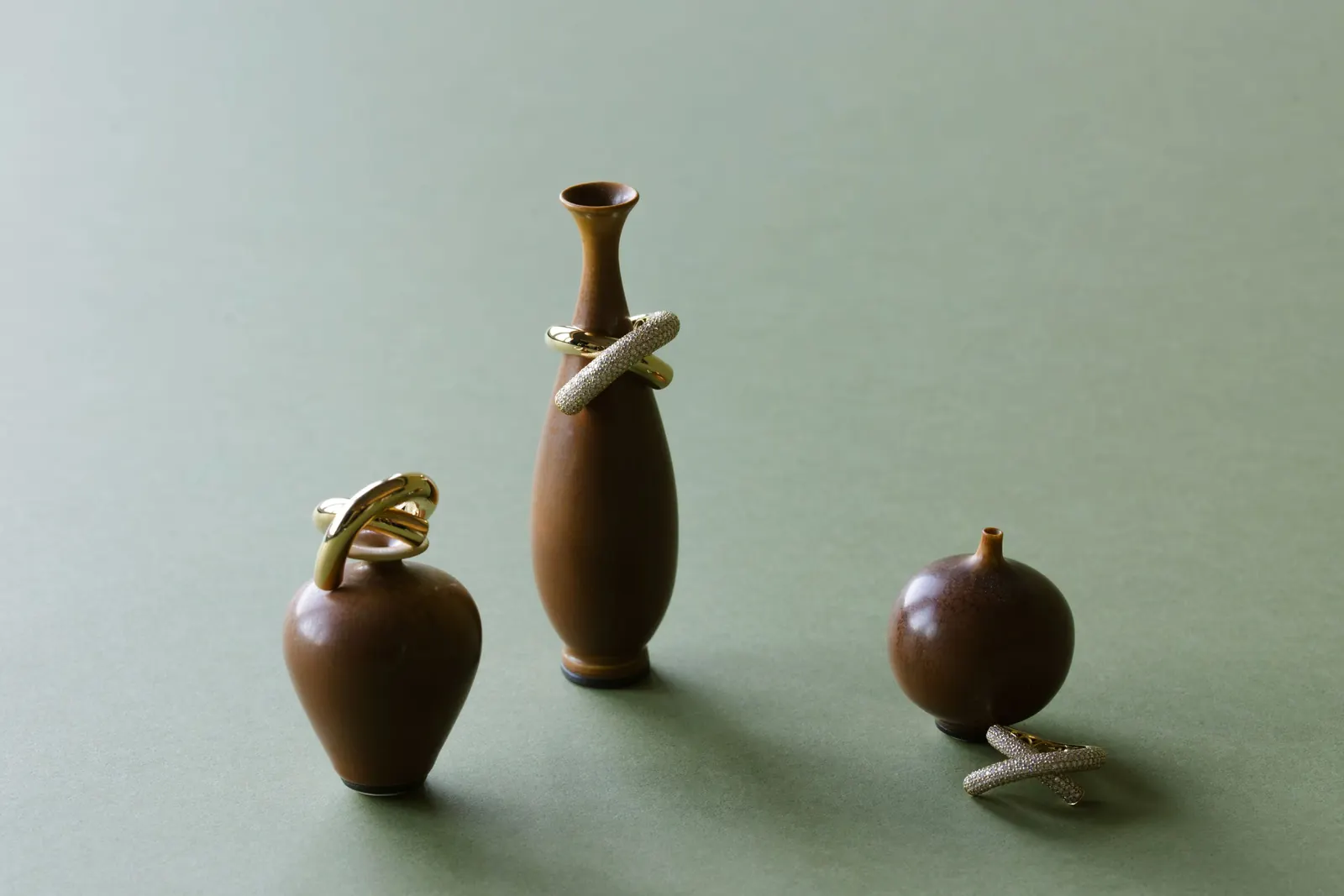 A still life composition featuring gold necklaces and rings from Englebert juxtaposed with a vintage Swedish ceramic vase.