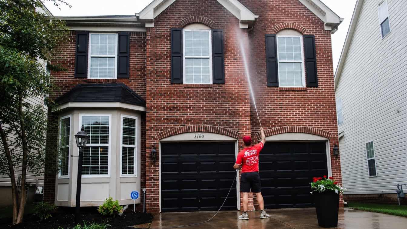 A pressure washing crew cleaning a historic brick and sandstone facade in Akron, Ohio, using low-pressure equipment to protect aging mortar