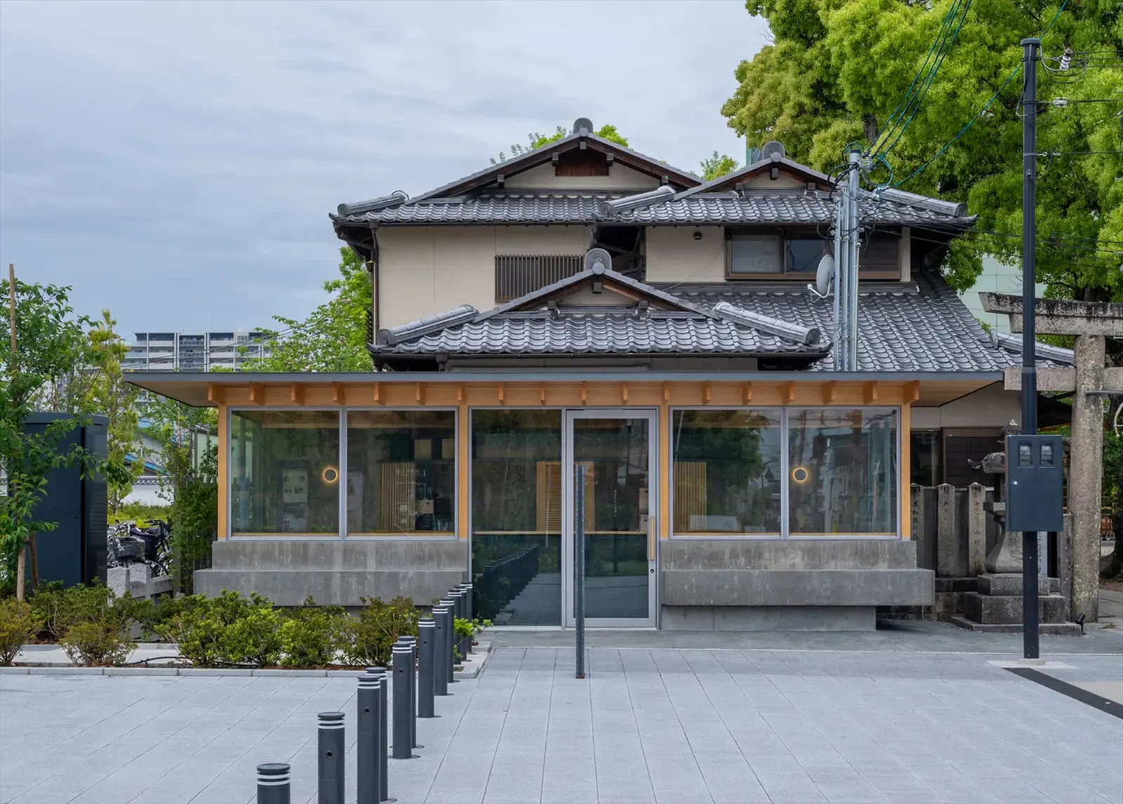 Exterior of Cafe N+ by Horibe Associates in Takatsuki, Japan, showing a timber-and-concrete design near a shrine and performing arts theater
