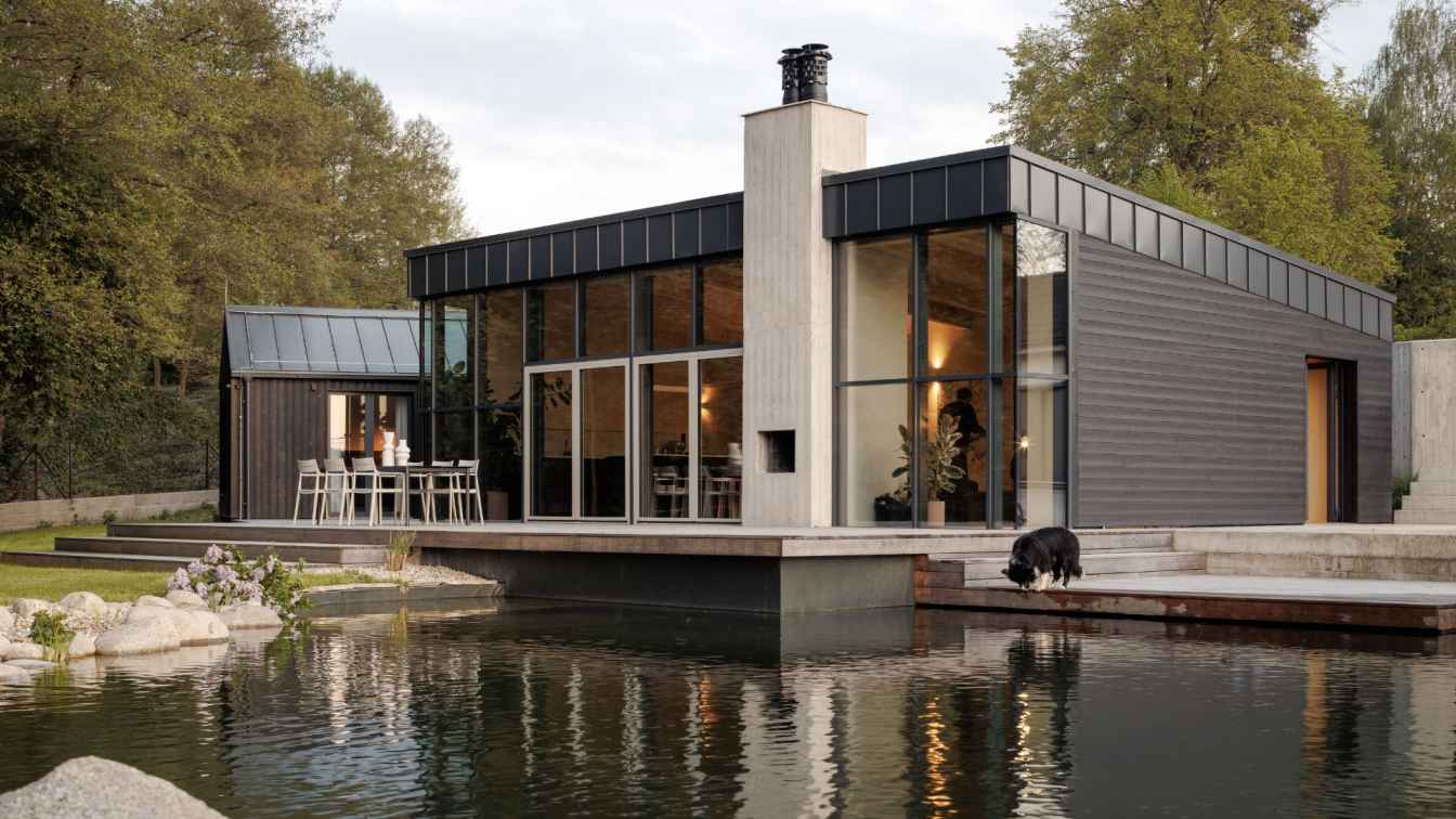 Charred larch weekend house by Anna Koukolová Architekti near Prague with large glazing facing a grove and stream