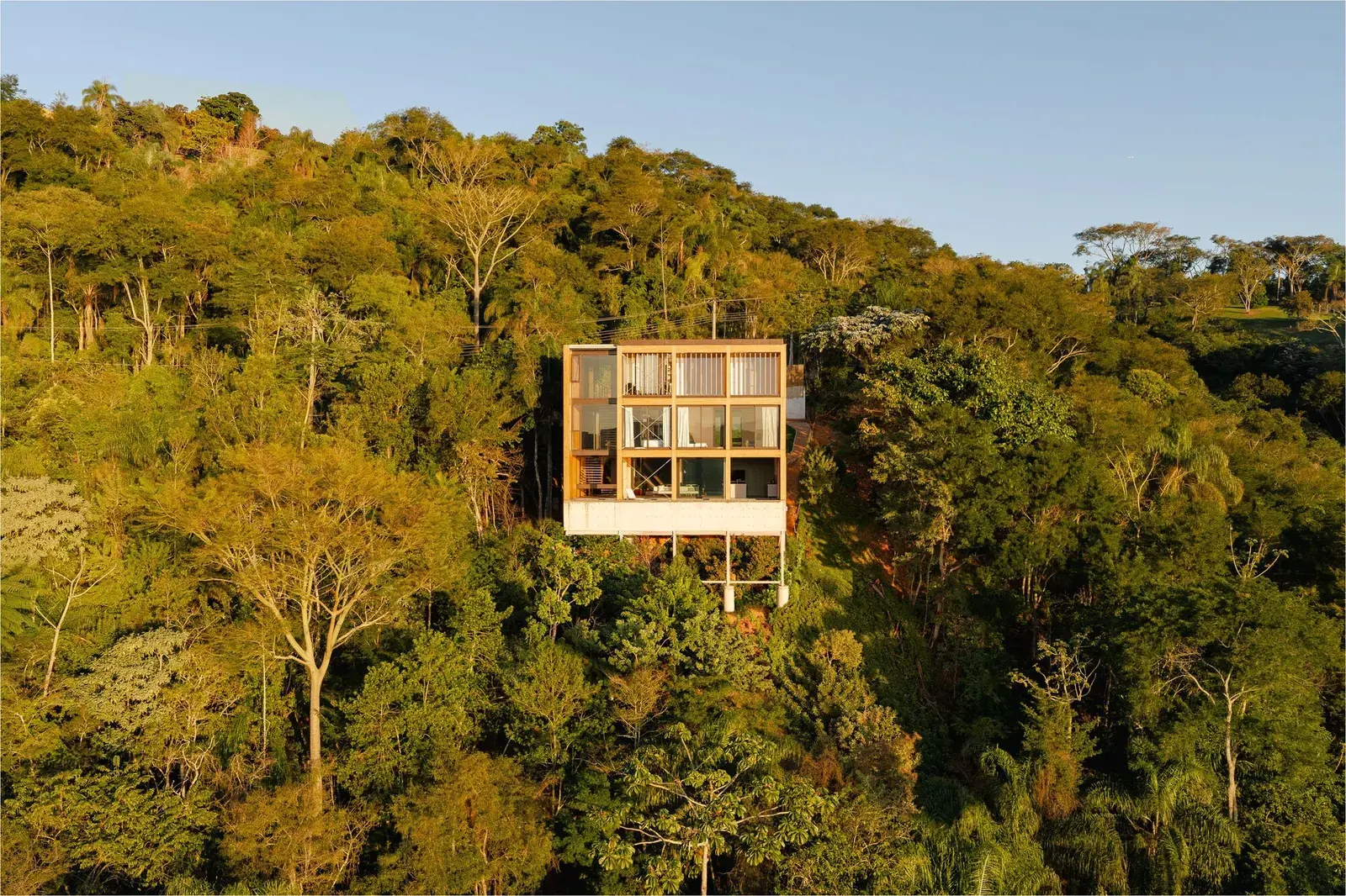 Rouxinol House, a contemporary hillside residence by Sergio Sampaio Archi + Tectônica, set among dense vegetation in Jacareí, Brazil