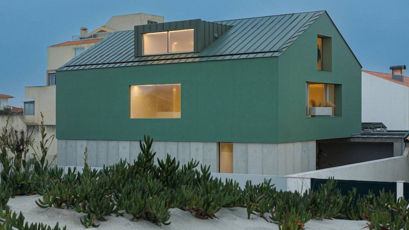 Casa Verde, a contemporary house with a green concrete exterior and zinc roof, set among dune vegetation in Costa Nova do Prado, Portugal