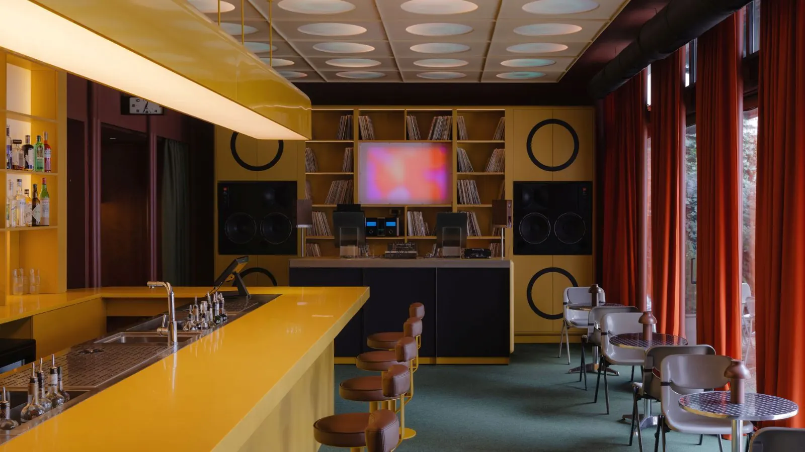 Yellow-lit interior of Esthetic Joys Embassy in Belgrade, with dark wood walls and vintage audio equipment