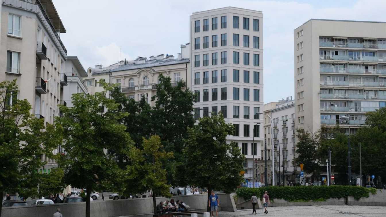Light-coloured facade of the Plac Politechniki 4 building by WXCA, a contemporary apartment block on a historic Warsaw square.