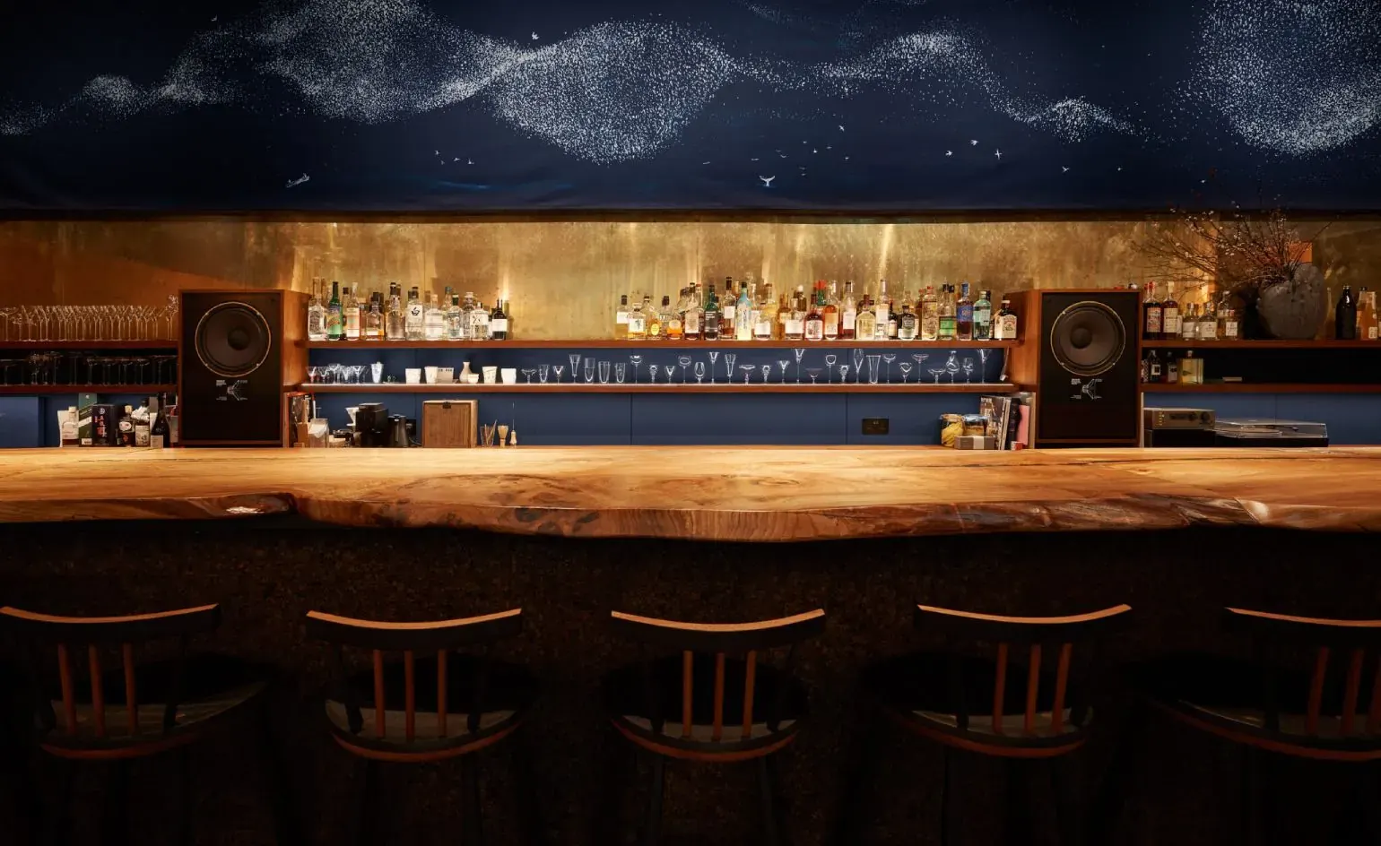 Interior of Waltz listening bar in Shoreditch, London, featuring a central bar, exposed speakers and ambient lighting